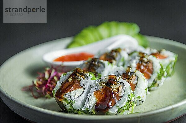 Perfect sushi  traditional Japanese cuisine. Delicious uramaki with sweet and sour sauce on the decorated plate  black background