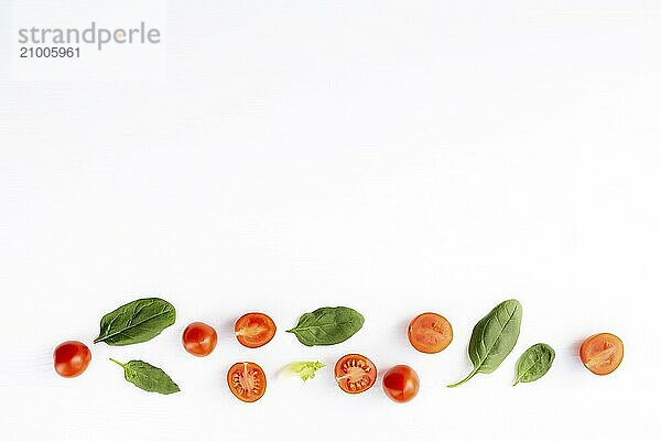 Flat lay with red cherry tomatoes and green spinach leaves on a white background. Healthy eating concept.