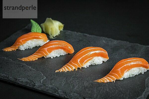 Perfect sushi  traditional Japanese cuisine. Delicious salmon kiguiri on the decorated plate  black background