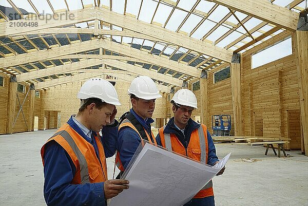 Three builders discuss the plan for a major construction job