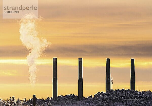 Steam rising from a funnel with four other smoke stacks in the distance