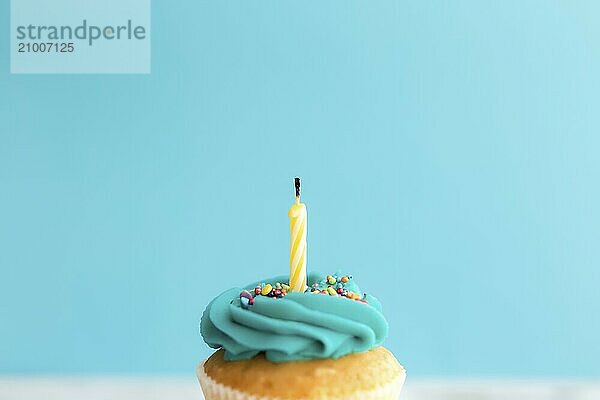 Birthday greetings concept. Blown out candle on a muffin or cupcake. Blue background