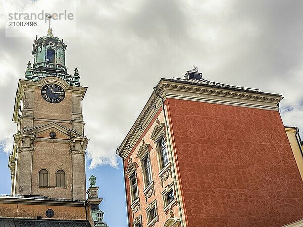 Historic tower with clock next to another building  sky with some clouds  stockholm  baltic sea  sweden  scandinavia