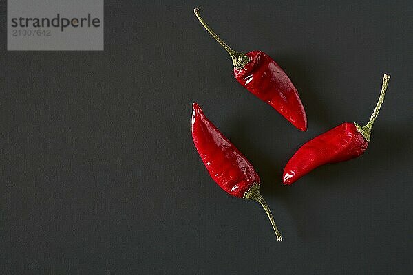 Red hot chili peppers over a dark background seen from above