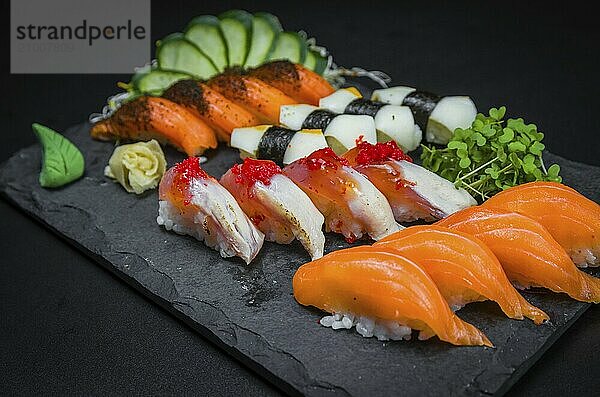 Sushi  traditional Japanese cuisine. Several delicious sushi on the decorated plate  black background. Group of sushi  Urakami  Nigori  Sushi jow  sashimi  tekamaki  etc