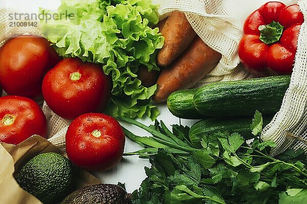 Fresh vegetables in eco bags on white table.