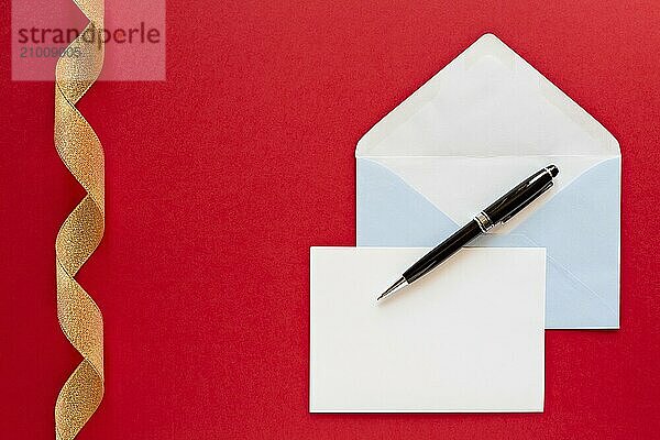 Christmas letter and pen over a red background with golden ribbon