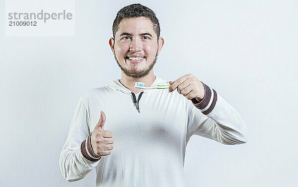 Happy man showing toothbrush with toothpaste gesturing OK. Handsome man holding brush with OK gesture isolated