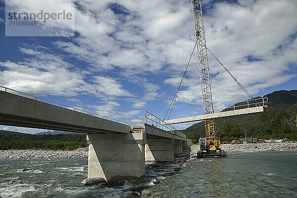 Builders construct a concrete bridge over a small river in Westland  New Zealand  Oceania