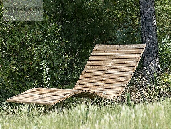 Wooden lounger in a meadow against a green background in the sunshine