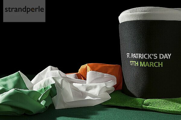 St Patrick day with hat and irish flag over a green table and black background