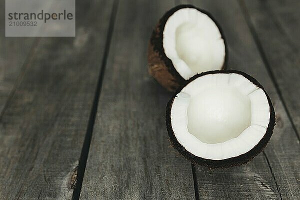 Broken coconuts on gray wooden background. White coconut pulp.