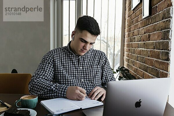 Man working at the laptop with a cup of coffee at home. Blurred background.