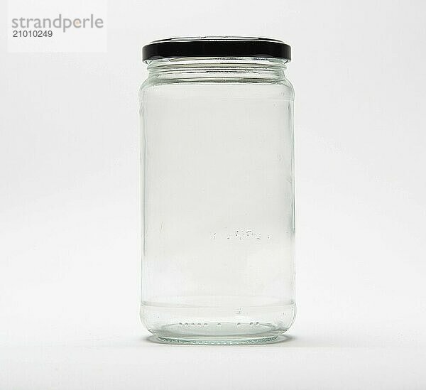 Empty glass jar with a black lid on white background