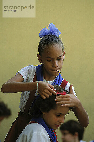 A school girl fixes a classmates hair at the 26 de Julio Elementary School in Santiago de Cuba.