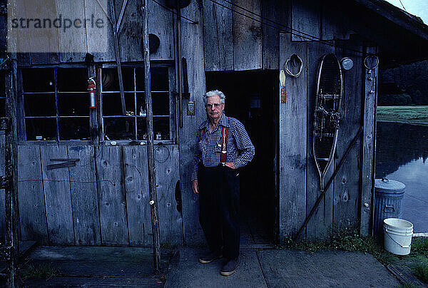 A man standing in front of his cabin  Alaska  USA.