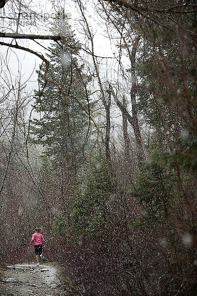 A woman trailruns in Little Cottonwood Canyon  Utah during a snow storm.