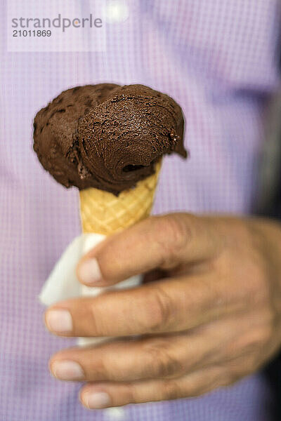 A chocolate gelato is held by a man in Montalcino  Italy.