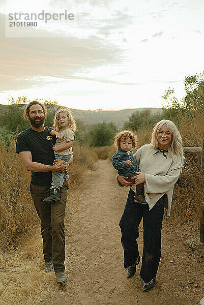 A family walking a mountain field at sunset