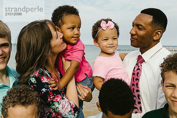 Multi racial family laugh and smile together on the beach