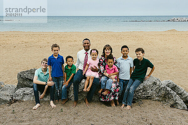 Mixed race family with many children together on beach smiling