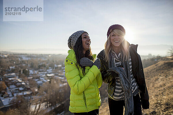 Two young women laugh outside in winter.