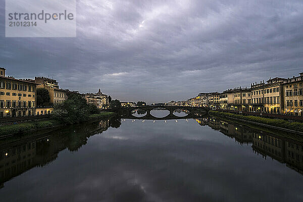 The Ponte Alla Carraia is illuminated at night over the Arno River in Florence  Italy.