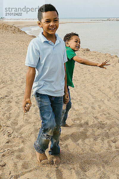 Brothers laughing together walking on the beach at lake