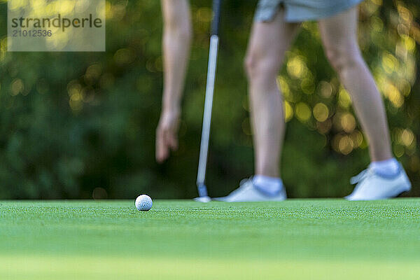 Golfer picking up ball on golf course