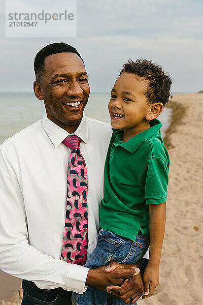 Diverse racially Father and son laugh together on beach