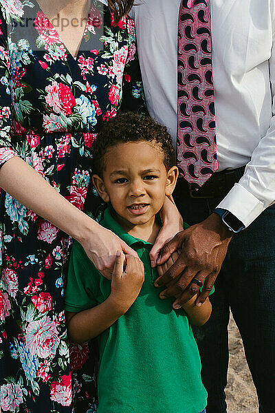 Mixed race child loved and hugged by white mom and black dad