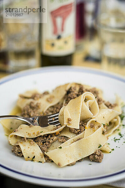 A pasta dish is served in Buonconvento  Itay with wine in the background.