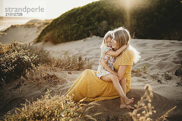 Mother and daughter hugging smiling at beach beautiful bond