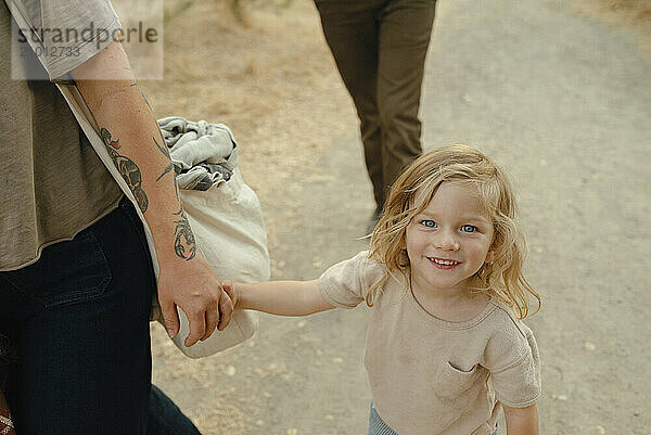 child with blonde hair holding moms hand