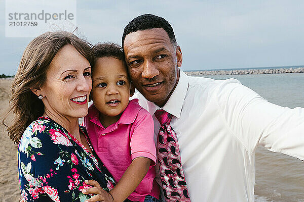 Smiling and laughing todder son of mixed race with father and mother