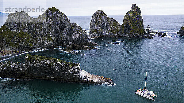 Catamaran near rock formations in Bering Sea  Kamchatka Peninsula  Russia