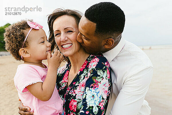 Black dad Caucasian mom love each other with toddler daughter