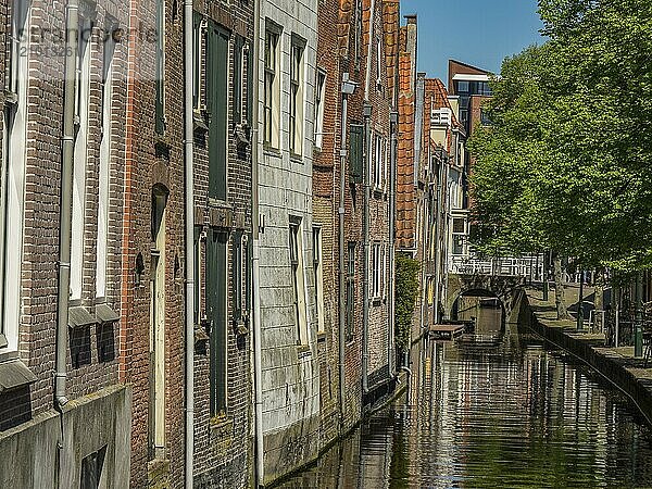 Row of old buildings on a canal with water and windows in sunny weather  alkmaar  the netherlands