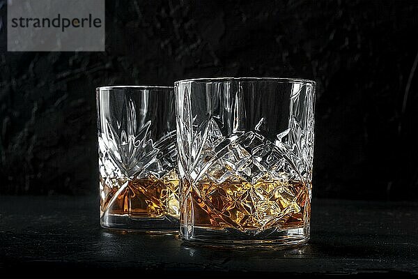 Whiskey in glasses with ice. Bourbon whisky on rocks on a dark background  elegant drinks  minimalist shot  side view  Food photography  Food photography