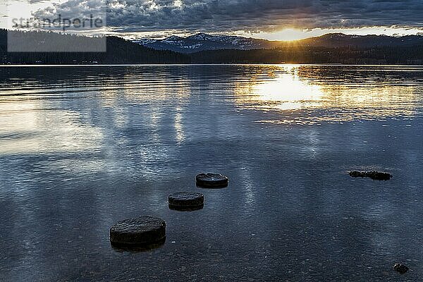 The sun is setting over the Coeur d'Alene Lake and the three round stones in north Idaho