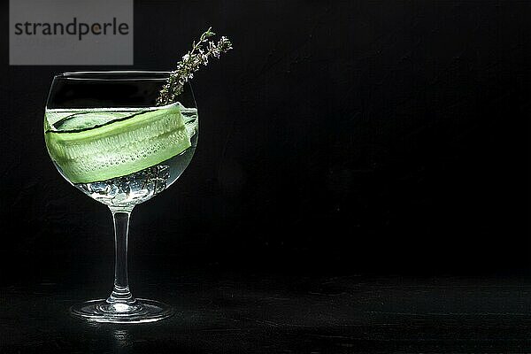 Fancy fresh cocktail. Gin and tonic drink with ice at a party  on a black background. Alcohol with cucumber and thyme  with copy space  Food photography