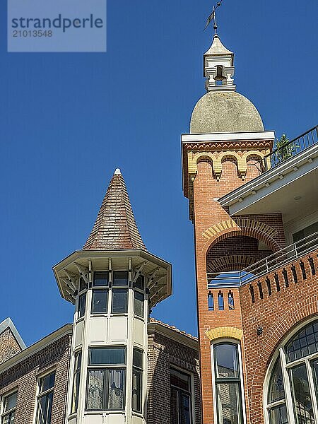 Two differently shaped towers of a brick building in front of a clear sky  one tower with dome  alkmaar  the netherlands