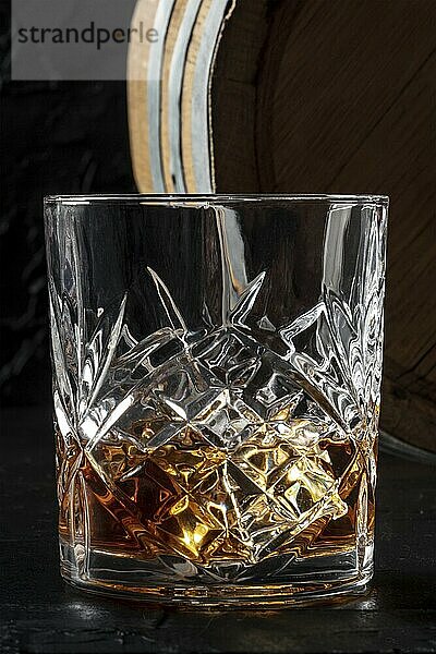 Whiskey in a glass with a barrel. Bourbon whisky and a cask on a dark background  a close-up of the classic luxury drink  Food photography