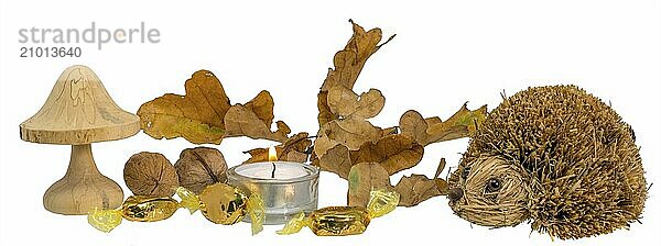 Christmas decoration with autumn leaves  candle  wooden mushroom and straw hedgehog against a white background