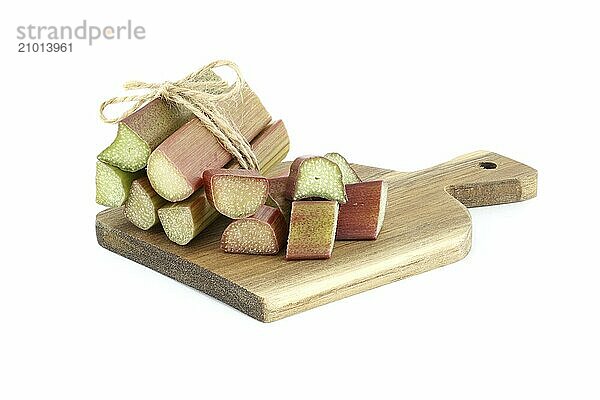 Variety of rhubarb stalks of varying colors from pale green to deep red on wooden cutting board isolated on white background