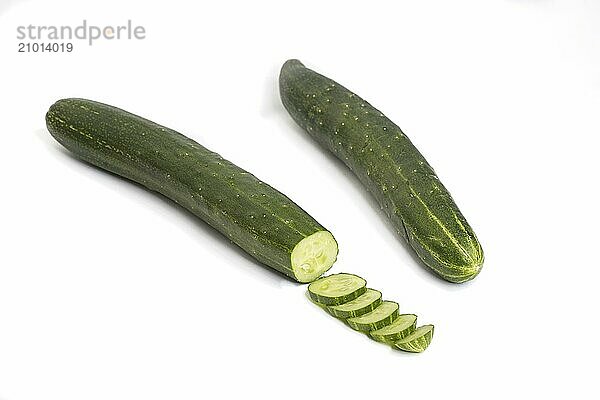 A close up photo of whole and partially sliced cucumbers set on a white background