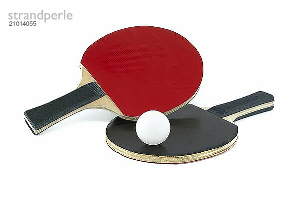 Isolated on a white background are two ping pong paddles and a ping pong ball  with one racket's surface appearing in red and the other in black