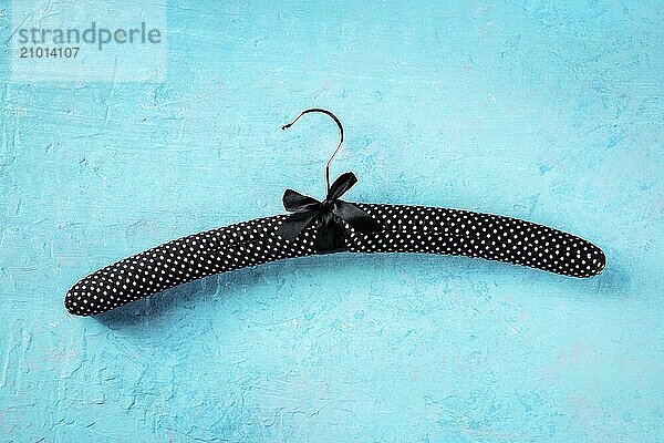 Fashion collection concept. Black satin hanger for delicate clothes  a flat lay on a blue background. Shopping  abstract design  Food photography