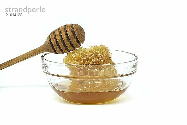 Glass bowl brimming with honey and wooden dipper resting on its rim isolated on white background  full depth of field