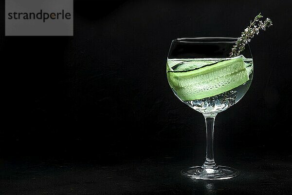 Fancy fresh cocktail. Gin and tonic drink with ice at a party  on a black background. Alcohol with cucumber and thyme  with a place for text  Food photography  Food photography